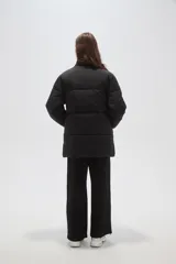 Campera puffer negra de corte holgado, con cuello alto, cierre frontal oculto y bolsillos laterales.