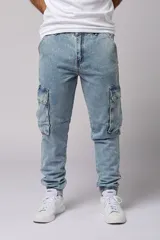 Pantalón jean celeste, corte jogger, con bolsillos cargo laterales y puños elásticos en los tobillos.