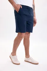 Bermuda deportiva de gabardina en color azul marino, con cintura elástica con cordón ajustable y bolsillos laterales.