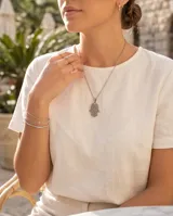 Dije de acero antialérgico con forma de mano de Hamsa, símbolo de protección y buena suerte, con detalles calados.