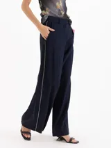 Pantalón sastre color negro de corte recto y tiro alto, confeccionado en mezcla de viscosa y elastano. Presenta bolsillos laterales, presillas para cinto y un delicado vivo decorativo a lo largo de los laterales.