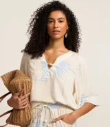 Blusa de manga corta en viscosa color beige, con escote en V con detalle de tira y cuenta de madera, y estampado geométrica y de follaje en tonos celestes.