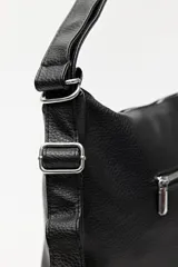 Cartera convertible en mochila, confeccionada en cuero sintético texturizado color marrón. Presenta un diseño con recortes, bolsillo frontal con cierre diagonal, herrajes metálicos plateados, asa superior y correas regulables.