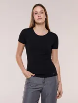 Remera básica de modal elastizado color blanco, con textura acanalada fina, escote redondo y mangas cortas. Presenta un pequeño logo metálico aplicado cerca del ruedo frontal.