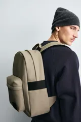 Mochila negra lisa con acabado engomado, compartimento principal con cierre de cremallera, bolsillo interior con cierre, bolsillo frontal con cierre, parte posterior acolchada con banda de sujeción para equipaje, asa de mano y dos asas de hombro ajustables y acolchadas.