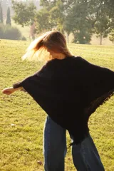 Poncho tejido en lana merino color marrón, con diseño de punto acanalado y terminación con flecos en el borde inferior. Incluye una pequeña etiqueta de cuero en la parte posterior.