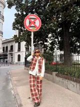 Chaleco de corte recto con estampado de cuadros en tonos rojos y marrones, con cierre frontal de botones y bolsillos laterales.