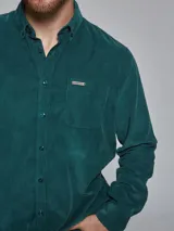 Camisa marrón de pana de manga larga con cuello abotonado y bolsillo en el pecho.