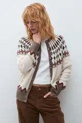 Cardigan de punto con diseño jacquard en tonos beige, marrón y rojo. Presenta cuello redondo, cierre frontal con botones y puños acanalados.