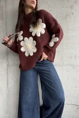 Sweater de punto color chocolate con diseño de flores grandes en relieve en color crema y centro amarillo. Presenta cuello alto, mangas largas y corte holgado.