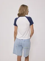 Remera azul marino de algodón con mangas cortas raglán blancas con ribete naranja y estampado ovalado con el logo de Rusty en el pecho.