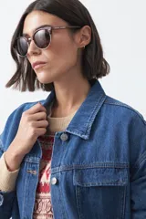 Sobrecamisa de jean color negro con silueta relajada, cuello camisero, cierre frontal con botones metálicos, bolsillos frontales y cinturón ajustable en la cintura.