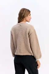 Saco de punto con textura tipo bouclé, de calce relajado y diseño levemente cropped. Cuenta con cuello redondo y cierre frontal mediante botones.