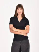 Remera negra de manga corta, con cuello polo y escote en V, y ribete blanco en el cuello y las mangas.