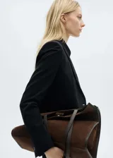 Chaqueta tipo blazer negra de corte recto y silueta slim. Presenta cuello con solapas de muesca, cierre frontal de un botón, mangas largas con puños abotonados y dos bolsillos delanteros con solapa.