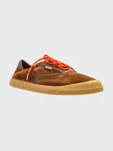 Zapatillas Moncler modelo Vera Leisure, confeccionadas en gamuza marrón con detalles en cuero tono sobre tono. Presentan cordones en color naranja vibrante y suela de goma texturizada en color caramelo.