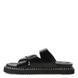 Sandalias planas Miss Carol Zelv de color negro, con diseño de tiras anchas cruzadas y hebillas metálicas doradas. Posee suela chunky con costuras visibles alrededor de la plataforma.