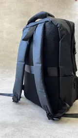 Mochila negra con múltiples bolsillos con cierre y manija superior.