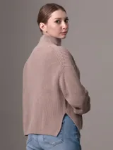 Sweater color beige de tejido de punto grueso con cuello alto y mangas largas.
