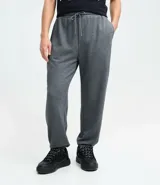 Pantalón tipo jogger de color negro, confeccionado en una mezcla de algodón y poliéster. Presenta cintura elástica con cordón ajustable, bolsillos laterales y puños elásticos en el ruedo.