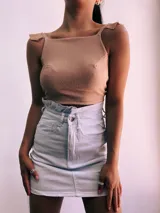 Crop top negro con textura brillante, breteles anchos con volados y espalda descubierta que se ata con lazos.