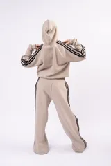 Pantalón deportivo tipo jogger de corte relajado, color negro con franjas laterales blancas y cintura elástica fruncida.