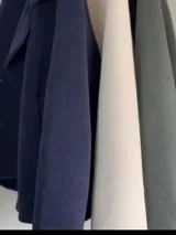 Chaqueta corta de paño color azul marino, con cuello solapa, cierre frontal de dos botones y mangas tres cuartos con diseño holgado.