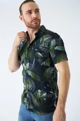 Camisa de manga corta con estampado botánico de hojas en tonos azul y blanco. Presenta cuello clásico, cierre frontal abotonado y corte slim.