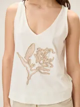 Musculosa de algodón color azul marino, con escote en V y un bordado artesanal de flor en el frente con contorno naranja y relleno dorado.