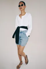 Shorts denim de tiro alto y corte relaxed, confeccionados en tejido vaquero celeste claro. Presentan trabillas en la cintura, diseño de cinco bolsillos, pliegues frontales y cierre con cremallera y botón metálico.