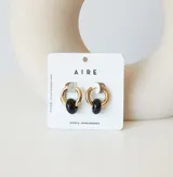 Aros de acero quirúrgico dorado con dije colgante en forma de argolla de piedra natural negra con destellos.