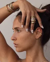 Earcuff de metal plateado, diseño orgánico y texturizado, que se ajusta al cartílago de la oreja sin necesidad de perforación.