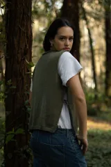 Chaleco corto de punto color verde oliva, con cuello amplio y aberturas laterales con lazos para ajustar.