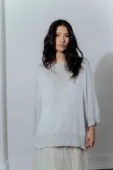 Buzo de hilo con tejido de punto fino, de corte holgado y mangas tres cuartos. Presenta un diseño versátil con cuello redondo amplio y acabado ligeramente brillante.