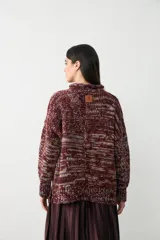 Sweater de punto grueso con cuello alto, confeccionado en una mezcla de hilos de colores que crean un efecto jaspeado en tonos bordó, naranja, amarillo y celeste.