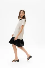 Vestido corto de algodón a rayas horizontales color beige, con cuello redondo negro y falda negra de lino.