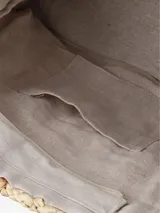 Bolso tipo tote de paja trenzada con diseño a rayas en tonos beige y verde oscuro, asas largas de cuero tostado y costuras visibles en los laterales.