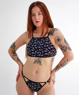 Top de escote alto y diseño reversible, con un lado liso en color negro y el otro con estampado floral. Presenta breteles finos y espalda regulable abierta.