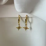Aros dorados tipo argolla con dije colgante en forma de estrella de ocho puntas con incrustaciones de strass.