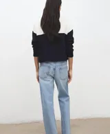 Jersey de punto de manga larga, con diseño bicolor en blanco y negro, cuello alto con cierre de cremallera corta.