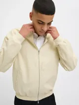 Campera bomber color beige de tejido liviano de lino y algodón, con cuello tipo baseball, mangas largas con puños de canalé, cierre con cremallera y bolsillos delanteros.