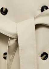 Trench coat de corte recto y diseño oversize, con cierre de doble botonadura, cuello de solapa ancha, bolsillos laterales y mangas largas con puños abotonados. Incluye cinturón desmontable y forro interior.