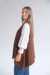 Chaleco largo abierto de tejido de punto color chocolate, con bolsillos frontales aplicados y diseño sin mangas.