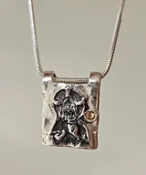 Collar dorado con dije rectangular con imagen religiosa y cristales azules.