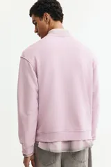 Buzo de tejido de mezcla de algodón de peso medio con interior cepillado suave. Modelo con cuello redondo ribeteado, hombros caídos y remate acanalado ancho en puños y bajo.