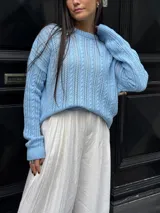 Sweater color crema tejido con diseño en ochos y cuello redondo.