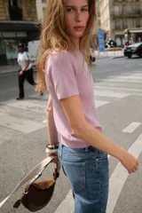 Jersey de punto color rosado claro, con cuello redondo y manga corta. Presenta una textura suave y un acabado ligeramente jaspeado.