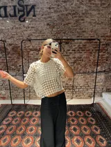 Blusa de tejido transparente color negro con diseño texturizado de mini flores en relieve, de mangas cortas y corte holgado.