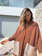 Saco tejido de punto en color marrón chocolate, con corte holgado y mangas anchas. Presenta cierre frontal con botones y dos bolsillos delanteros grandes en material metalizado color champán.