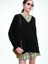 Sweater negro de punto con escote en V profundo, hombros caídos y diseño amplio de calce relajado.